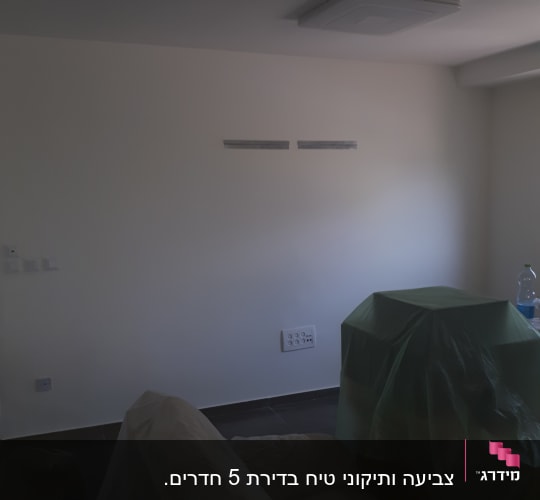 קיר צבוע עם רהיטים מכוסים בניילון
